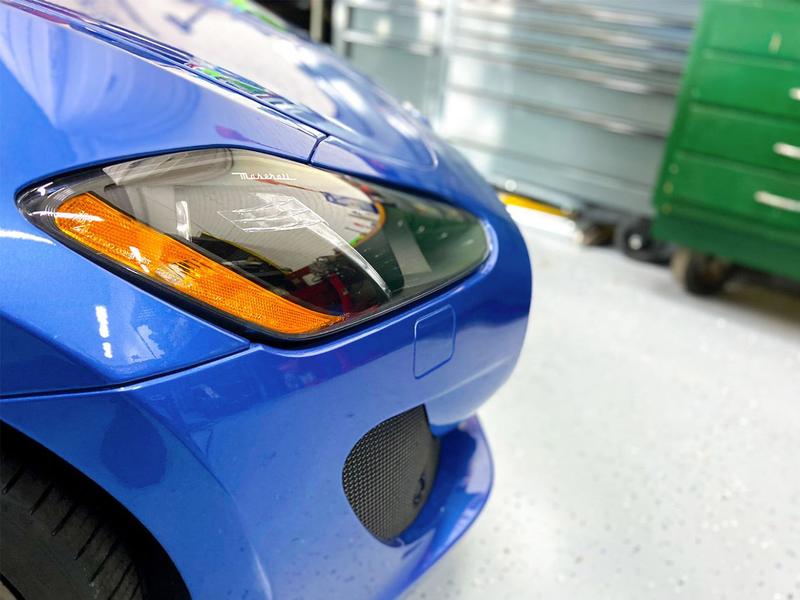 Front corner close up of a blue maserati showing the headlight