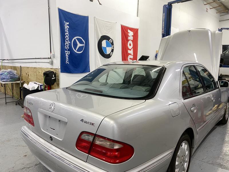 Silver Mercedes W210 E320 by BMW, Mercedes, and Motul flags