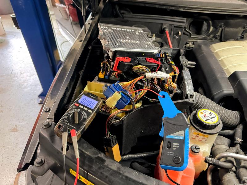 Underhood electrical compartment of Range Rover with oscilloscope amp clamp and multimeter